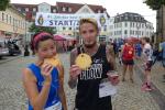 Sabine B&ouml;rner kann es nicht lassen und verputzt ihre Lorbeeren direkt nach dem Start. Da Stefan Otto mit dem Pokal &uuml;ber den Gesamtsieg auf der Halbmarathondistanz ausreichend Troph&auml;en mit nach Hause nehmen wird, verschenkt er seine frisch gebackene Jakobsmuschel an einen anderen hungrigen Finisher.
